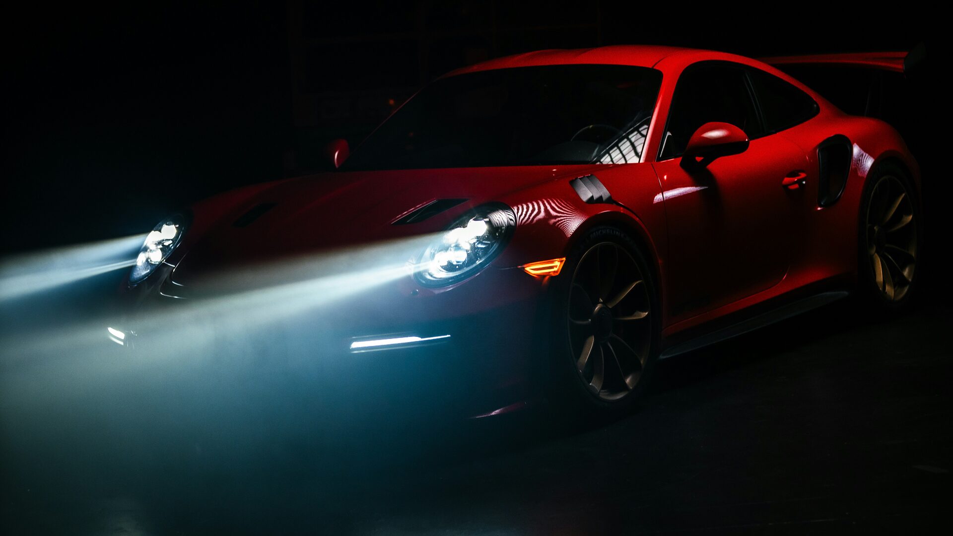 Porsche 911 GT3 RS rojo de noche con los faros encendidos